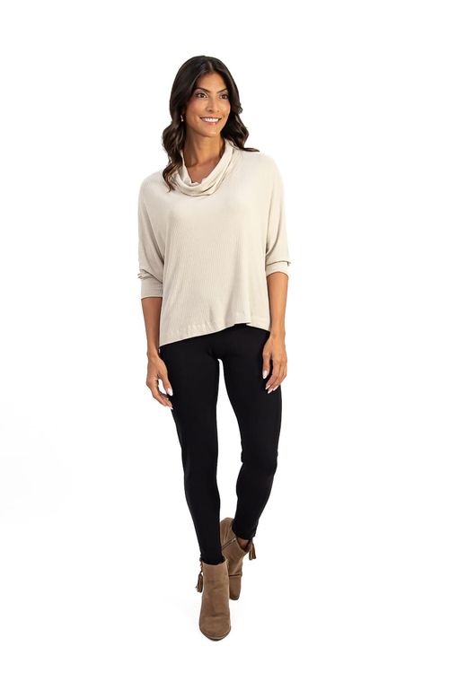 Modelo vestindo calça legging montaria preta com blusa bege e botas marrons, em pose frontal.