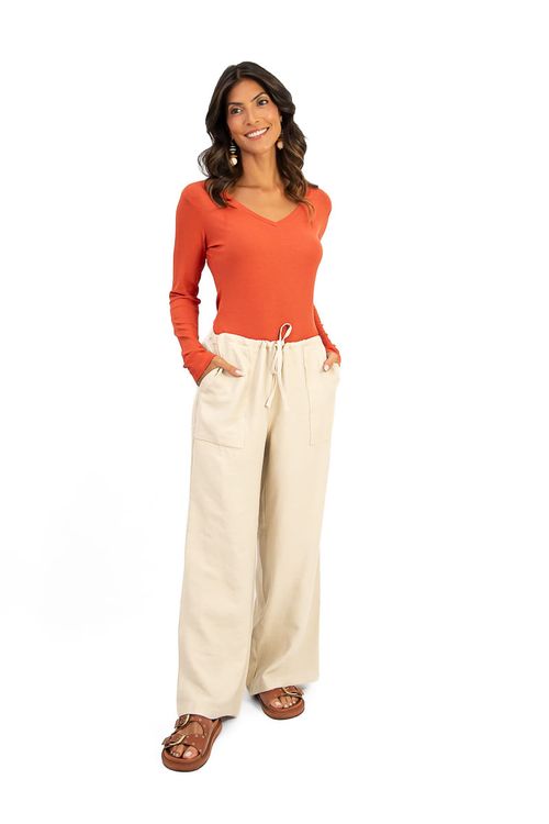 Modelo vestindo calça reta bege com blusa laranja, vista frontal.