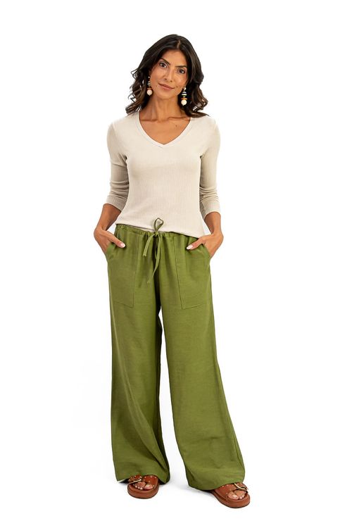 Vista frontal da calça reta verde com blusa bege.
