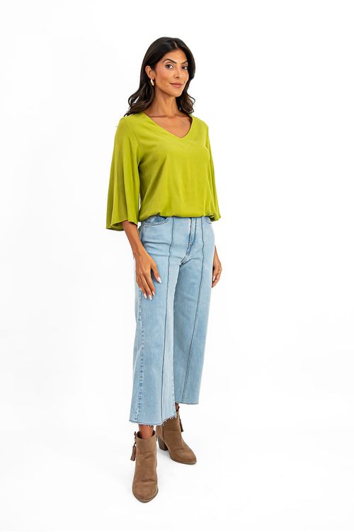 Blusa-verde-com-manga-sino-e-decote-em-V-combinada-com-calca-jeans-e-botas-marrons.