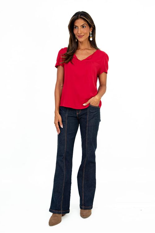 Modelo vestindo blusa vermelha com calça jeans, vista completa.