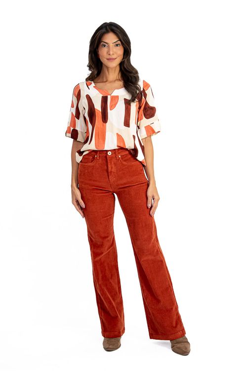 Modelo vestindo calça wide leg de veludo canelado caramelo com blusa estampada, vista frontal.