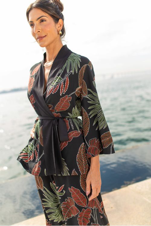 Kimono-confeccionado-em-tecido-plano-de-viscose-apresentando-uma-estampa-botanica-de-folhagem-em-tons-de-verde-e-vermelho-sobre-fundo-preto.-Possui-mangas-3-4-largas-abertura-lateral-pala-e-faixa-para-ajuste-proporcionando-um-caimento-relaxado-e-fluido.-Ideal-para-ocasioes-casuais-e-elegantes.