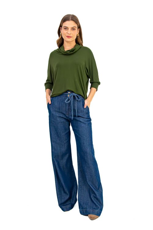 Vista completa da blusa verde escuro com maxi gola e mangas morcego, combinada com calça jeans.