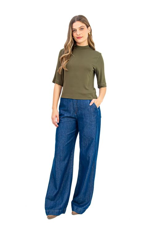 Visual completo: Modelo vestindo blusa gola alta em verde militar combinada com calça jeans corte wide-leg azul, criando um look casual chique.