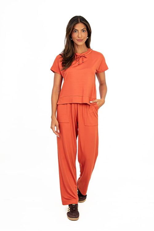 Imagem de uma modelo mostrando detalhes da calça reta cerâmica, incluindo os bolsos faca chapados.