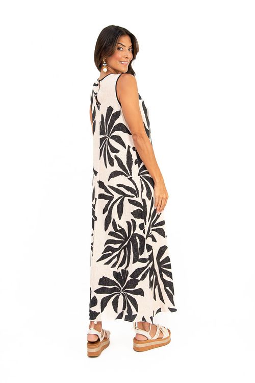 Detalhe das costas do vestido midi em viscose mostrando fechamento por botão, decote com pequena abertura em gota e estampa botânica de folhas pretas sobre off white