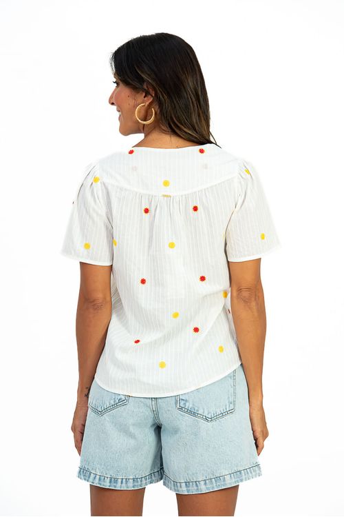 Side-view-of-the-embroidered-blouse-showing-a-loose-fit-back-yoke-and-wide-sleeves-combined-with-denim-shorts-and-sandals