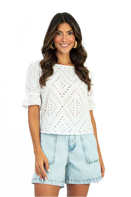 Frente da blusa branca em algodão laise com broderie geométrica e decote canoa, usada com shorts jeans claros — blusa feminina manga 3/4 bufante