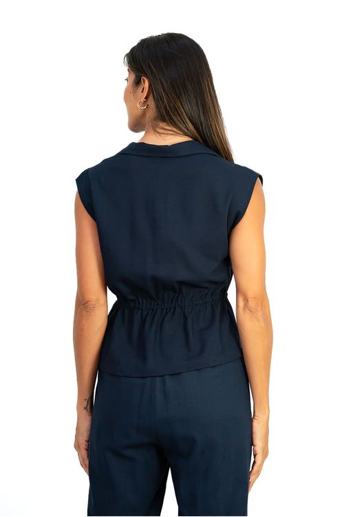 Blusa Amélia Cropped marinho vista costas em modelo mostrando pala com túnel ajustável e recorte peplum na barra, acabamento em tecido liso.