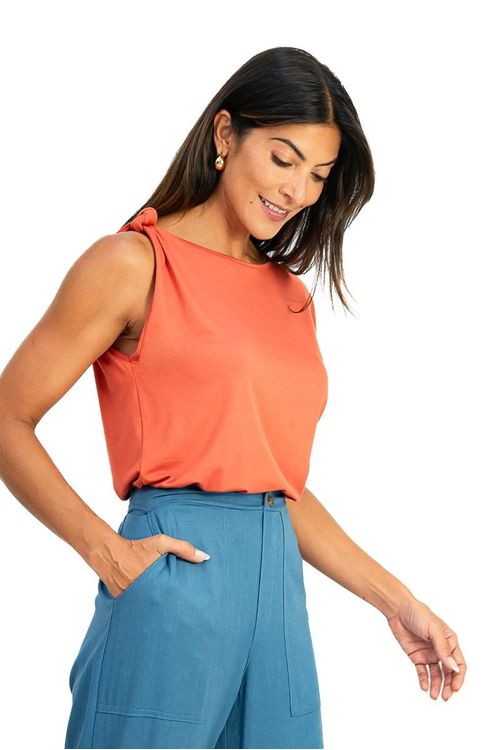 Close da calça cropped em linho azul mostrando detalhe do bolso faca frontal, pala com botões decorativos e cós com elástico na região posterior.