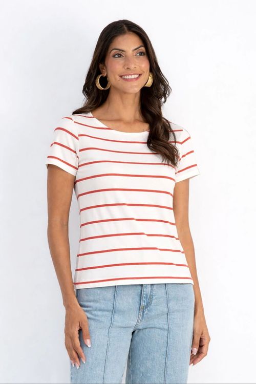 Modelo vestindo blusa branca com listras horizontais cor cerâmica em malha viscose crepe, decote canoa e meia-manga, silhueta reta combinada com jeans claro.