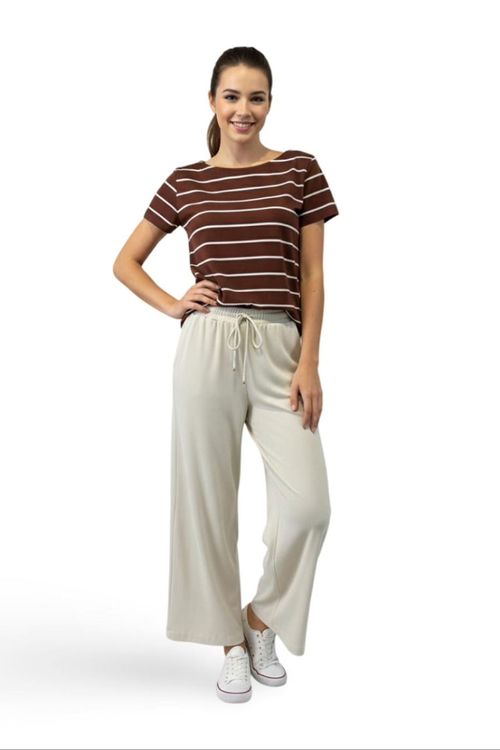 Modelo vestindo blusa listrada em tom café com calça leve off-white, criando um conjunto casual elegante.