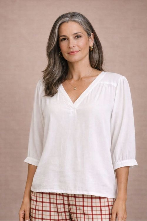 Bata off white em viscose slub, close no decote V com pesponto aparente e manga três quartos com punho e botão, detalhe de tecido e acabamento