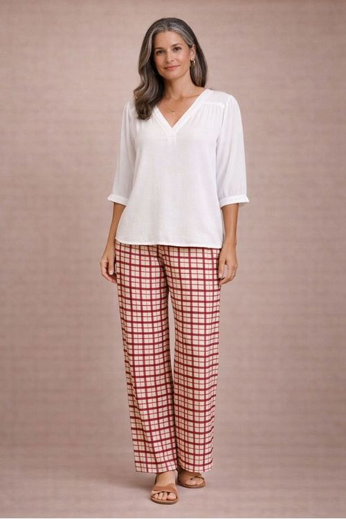 Look inteiro com bata decote V off white em viscose slub combinada com calça xadrez bege e vermelha e sandálias, vista frontal mostrando caimento fluido