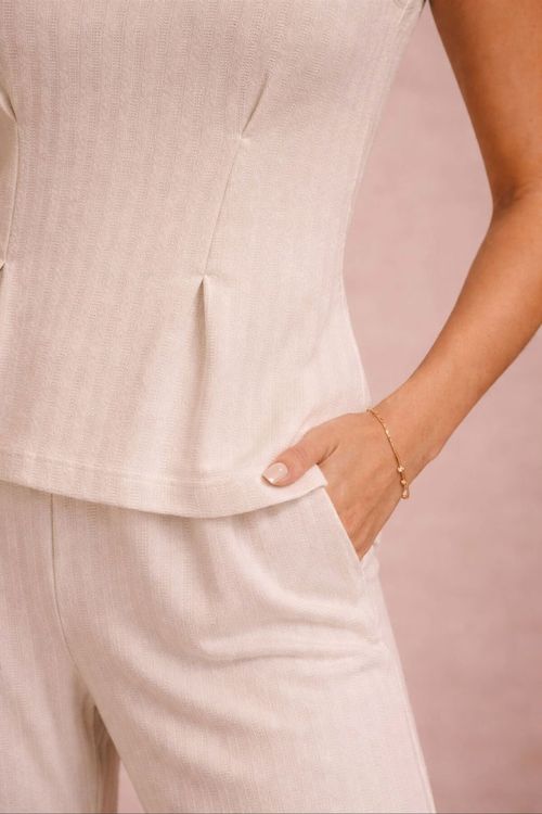 Detalhe da blusa de tricô com textura baunilha mostrando penses frontais e acabamento texturizado do tecido, destacando o caimento e a barra peplum.