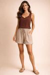 Modelo-usando-short-linho-bege-risca-de-giz-com-regata-marrom-e-sandalias-rasteiras-mostrando-corte-reto-cos-elastico-com-fru-fru-e-bolsos-frontais---look-casual-e-fresco