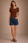Look-frontal-corpo-inteiro-com-blusa-tricot-canelado-marrom-chocolate-shorts-jeans-de-lavagem-media-e-sandalias-rasteiras--decote-canoa-e-caimento-levemente-ajustado-em-destaque.