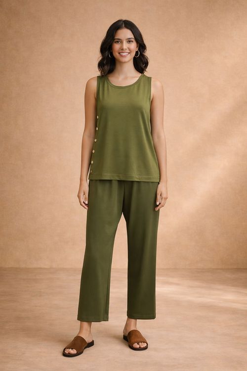 Modelo com look completo: blusa verde sem mangas de decote canoa com botões laterais combinada a calça reta verde e sandálias rasteiras, visual casual e elegante