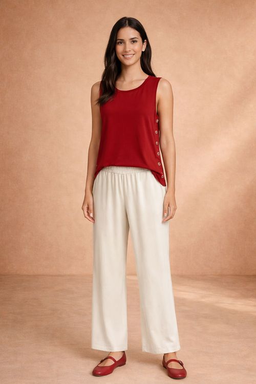 Modelo vestindo blusa vinho sem mangas em malha viscose com decote canoa e botões laterais, caimento fluido; look com calça pantalona creme e sapatilha vinho - blusa vinho viscose decote canoa botões laterais