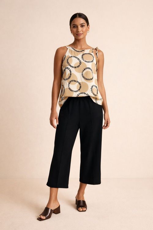 Mulher vestindo blusa estampada com padrão geométrico Caraíva, combinada com calça preta.