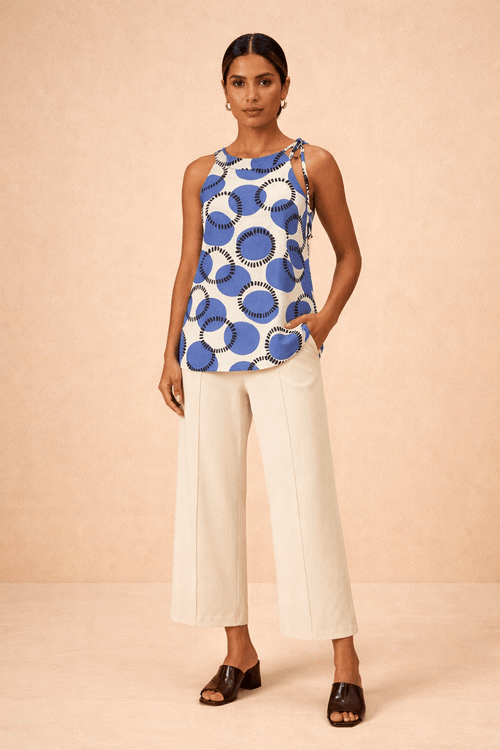 Frente de blusa estampada em design geométrico com base branca e detalhes azul cobalto, modelagem sem mangas com decote nas costas.