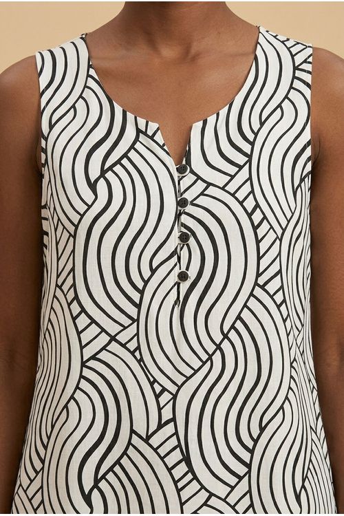 Detalhe do tecido da blusa estampada, mostrando o padrão geométrico em preto e branco e os botões frontais.