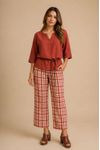 Blusa feminina terracota com decote canoa e mangas 3/4, combinada com calça xadrez e sandálias.