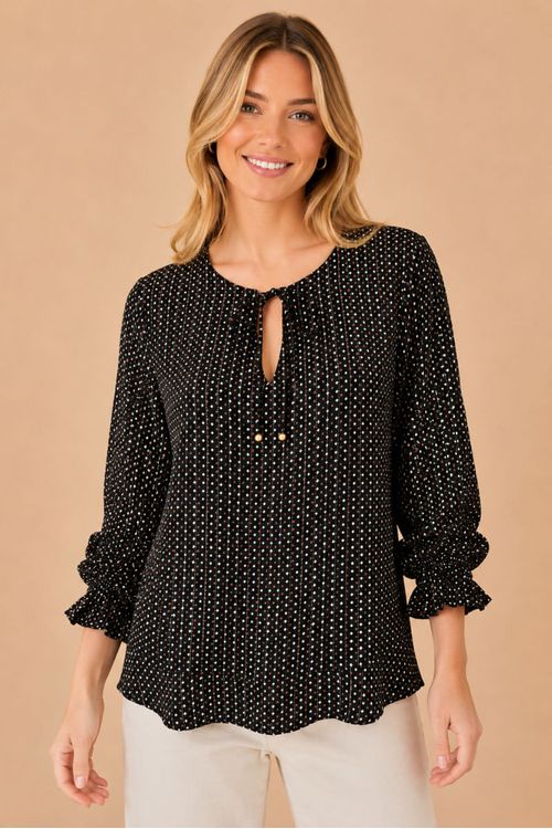 Vista frontal da blusa feminina estampada preta Bossa, com manga longa bufante, decote em V com amarração e estampa geométrica delicada, combinada com calça clara.